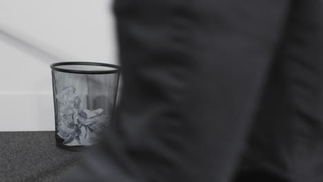 Wide-Shot-of-Person-Walking-Past-Bin-as-He-Throws-Paper-In