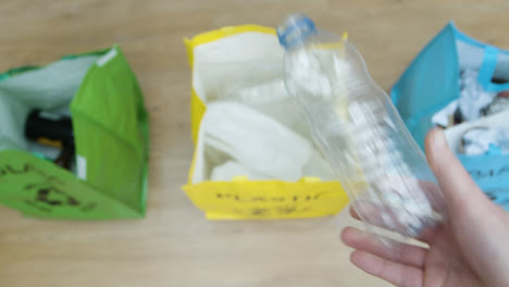 Top-Down-Pull-Focus-Shot-of-Person-Throwing-Plastic-Bottle-into-Recycling-Bag