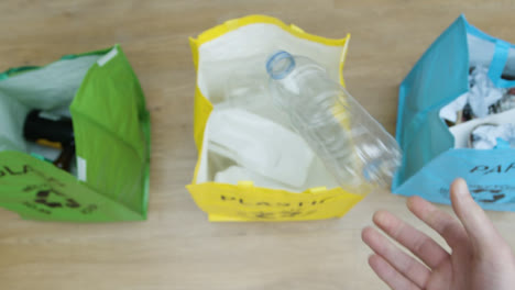 Top-Down-Pull-Focus-Shot-of-a-Person-Throwing-Plastic-Bottle-into-Recycling-Bag