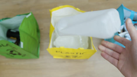 Top-Down-Pull-Focus-Shot-of-a-Person-Throwing-Plastic-Carton-into-Recycling-Bag