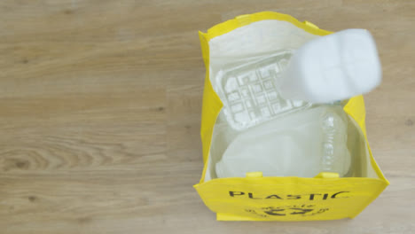 Top-Down-Shot-of-Person-Throwing-Plastic-Carton-into-Recycling-Bag-with-Copy-Space