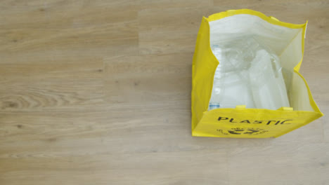 Top-Down-Shot-of-Person-Throwing-Plastic-Bottle-into-a-Recycling-Bag-with-Copy-Space