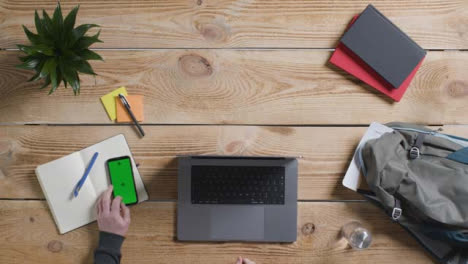 Top-Down-Shot-of-Person-Working-On-Apple-MacBook-Pro-with-Green-Screen-Phone-02