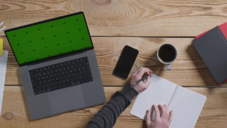 Top-Down-Shot-of-Person-Working-at-Desk-with-Green-Screen-Apple-MacBook-Pro-01