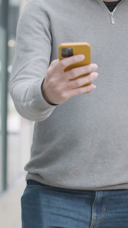 Toma-De-Seguimiento-Vertical-De-Un-Estudiante-Caminando-Con-El-Teléfono