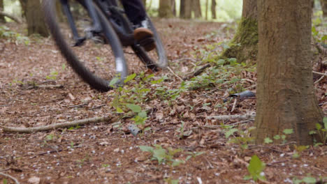 Close-Up-Of-Man-On-Mountain-Bike-Cycling-Along-Trail-Through-Countryside-And-Woodland
