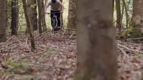 Close-Up-Rear-View-Of-Young-Man-On-Mountain-Bike-Cycling-Along-Trail-Through-Woodland
