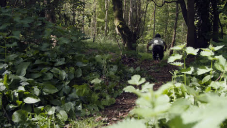 Low-Angle-Shot-Of-Man-On-Mountain-Bike-Cycling-Along-Dirt-Trail-Through-Woodland