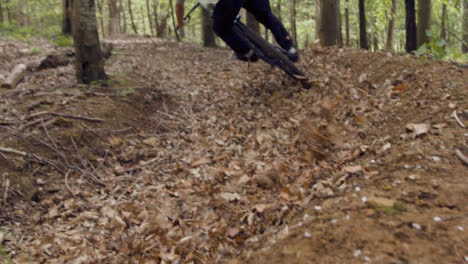 Tiro-De-ángulo-Bajo-Del-Hombre-En-Bicicleta-De-Montaña-En-Bicicleta-A-Lo-Largo-Del-Camino-De-Tierra-A-Través-De-Hojas-En-El-Bosque-2