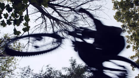 Low-Angle-Shot-Of-Man-On-Mountain-Bike-Jumping-Over-Camera-Riding-Through-Woodland