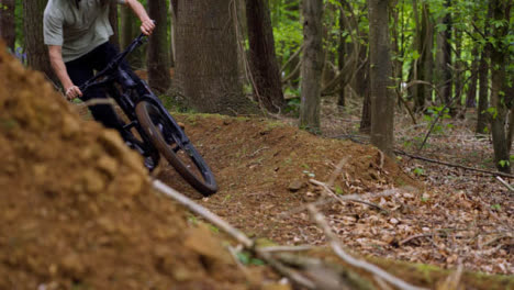 Zeitlupenaufnahme-Eines-Mannes-Auf-Dem-Mountainbike,-Der-In-Der-Luft-Auf-Einem-Feldweg-Durch-Den-Wald-Springt