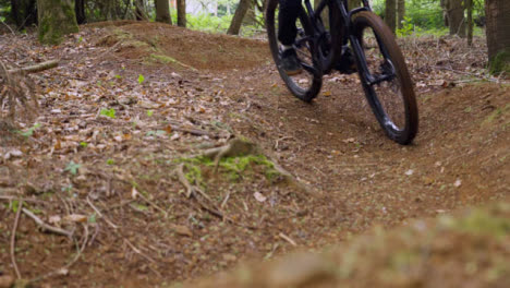 Close-Up-Slow-Motion-Of-Man-On-Mountain-Bike-Cycling-Along-Dirt-Trail-Through-Woodland