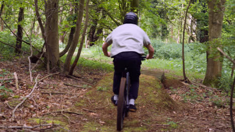 Disparo-En-Cámara-Lenta-De-Un-Hombre-En-Bicicleta-De-Montaña-Haciendo-Un-Salto-En-El-Aire-En-Un-Sendero-De-Tierra-A-Través-Del-Bosque-8