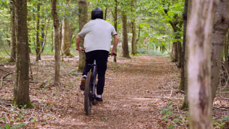 Slow-Motion-Shot-Of-Man-On-Mountain-Bike-Cycling-Along-Trail-Through-Woodland-