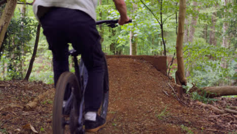 Slow-Motion-Shot-Of-Man-On-Mountain-Bike-Making-Mid-Air-Jumps-On-Dirt-Trail-Through-Woodland-5