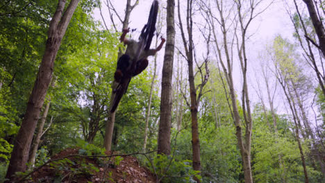 Zeitlupenaufnahme-Eines-Mannes-Auf-Einem-Mountainbike,-Der-In-Der-Luft-Auf-Einem-Feldweg-Durch-Wald-3-Springt