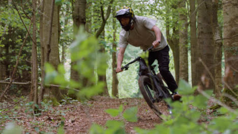 Slow-Motion-Shot-Of-Man-On-Mountain-Bike-Cycling-Along-Trail-Through-Woodland-