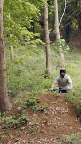 Close-Up-Vertical-Video-Of-Man-On-Mountain-Bike-Cycling-Along-Dirt-Trail-Through-Woodland-4