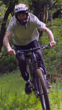 Drone-Vertical-Video-Tracking-Man-On-Mountain-Bike-Cycling-Doing-Mid-Air-Jump-On-Trail-Through-Woodland-3