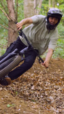 Vertical-Video-Of-Man-On-Mountain-Bike-Making-Mid-Air-Jump-On-Dirt-Trail-Through-Woodland-1