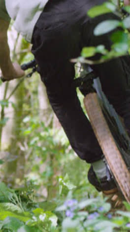 Close-Up-Vertical-Video-Of-Man-On-Mountain-Bike-Cycling-Along-Dirt-Trail-Through-Woodland