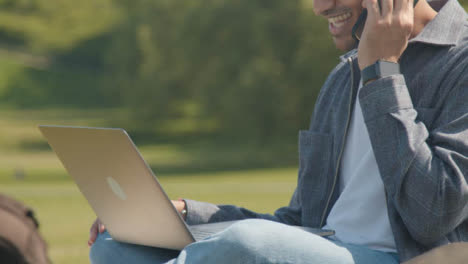 Handheld-Shot-of-a-Young-Man-In-Park-Talking-On-His-Phone