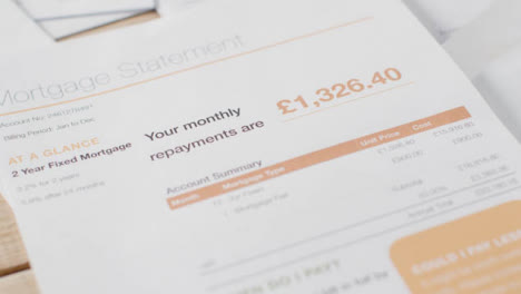 Close-Up-Of-Person-Throwing-UK-Mortgage-Statement-Onto-Bills-On-Table