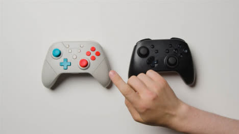 Overhead-Studio-Shot-Of-Hand-Reaching-In-To-Choose-Video-Game-Controllers