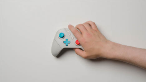 Overhead-Studio-Shot-Of-Hand-Reaching-In-To-Pick-Up-Video-Game-Controller-3