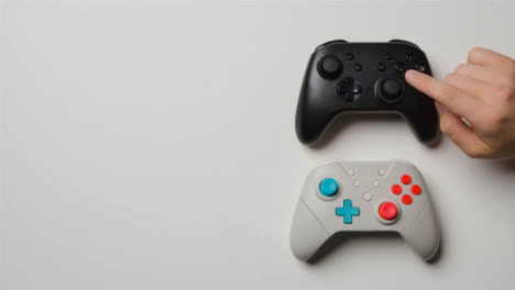 Overhead-Studio-Shot-Of-Hand-Reaching-In-To-Choose-Video-Game-Controllers-2