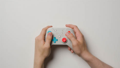 Overhead-Studio-Shot-Of-Hands-Using-And-Playing-Video-Game-Controller-2