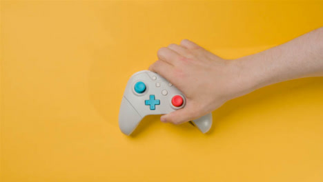 Overhead-Studio-Shot-Of-Hand-Reaching-In-To-Swap-Video-Game-Controllers