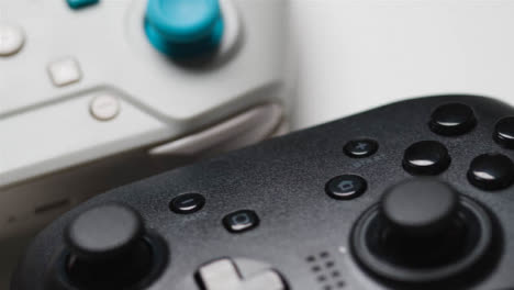 Close-Up-Hand-Picking-Up-One-Of-Two-Video-Game-Controllers-White-Background-1