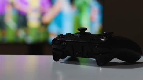 Close-Up-Shot-Of-Video-Game-Controller-Sports-Game-On-Screen-In-Background-1
