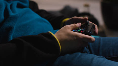 Side-On-Close-Up-Hands-Man-Playing-Video-Game-Controller-Sitting-Sofa-At-Home
