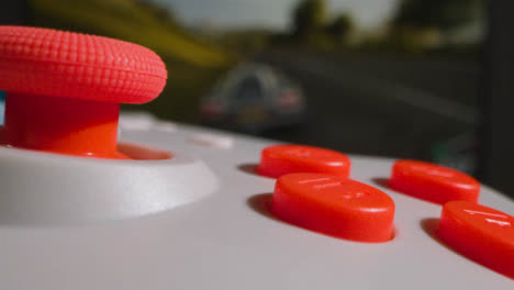 Close-Up-Macro-Video-Game-Controller-Driving-Game-On-Screen-In-Background