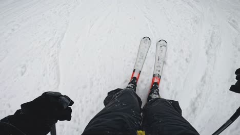 POV-Aufnahme-Eines-Skifahrers,-Der-Einen-Schneebedeckten-Hang-Hinunterfährt-Und-Auf-Skier-Hinunterblickt