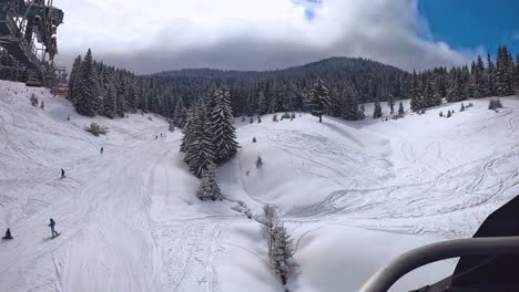 POV-Aufnahme-Eines-Skifahrers-Am-Sessellift-über-Schneebedeckte-Berge-Und-Bäume-1