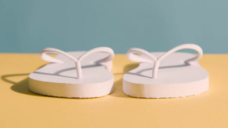 Summer-Concept-Of-Hand-Picking-Up-Flip-Flops-On-Yellow-Blue-Background