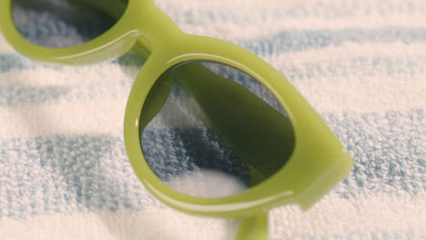 Summer-Holiday-Vacation-Concept-Of-Sunglasses-Rotating-On-Beach-Towel