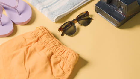 Summer-Holiday-Concept-Of-Camera-Shorts-Sunglasses-Flip-Flops-On-Beach-Towel