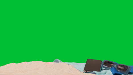 Summer-Holiday-Concept-Of-Sunglasses-Mobile-Phone-Beach-Towel-On-Sand-Against-Green-Screen