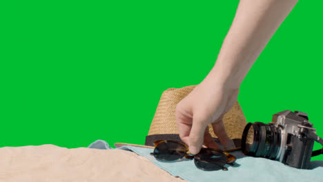 Summer-Holiday-Concept-Of-Sunglasses-Sun-Hat-Camera-Beach-Towel-On-Sand-Against-Green-Screen-1