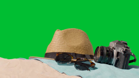 Summer-Holiday-Concept-Of-Sunglasses-Sun-Hat-Camera-Beach-Towel-On-Sand-Against-Green-Screen-3