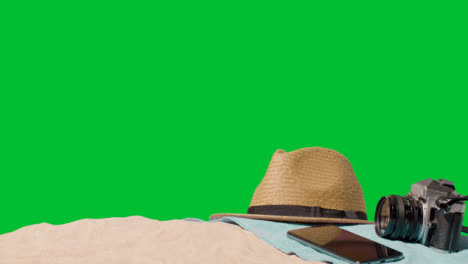 Summer-Holiday-Concept-Of-Camera-Sun-Hat-Mobile-Phone-Beach-Towel-On-Sand-Against-Green-Screen-5
