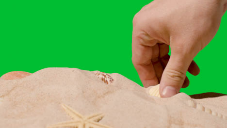 Summer-Holiday-Concept-Person-Collecting-Shells-Starfish-On-Sandy-Beach-Against-Green-Screen-1