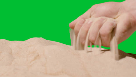 Sommerferienkonzept-Mit-Der-Hand,-Die-Sand-Vom-Strand-Gegen-Grünen-Bildschirm-Aufhebt