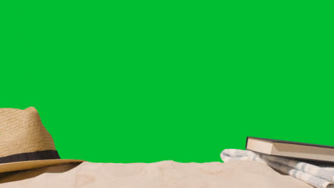 Summer-Holiday-Concept-Of-Book-Sun-Hat-Beach-Towel-On-Sand-Against-Green-Screen-2