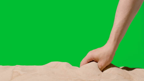Sommerferienkonzept-Mit-Der-Hand,-Die-Sand-Vom-Strand-Gegen-Grünen-Bildschirm-2-Aufhebt