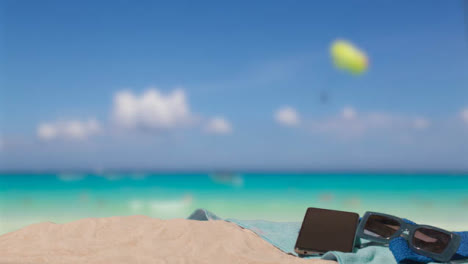 Sommerferienkonzept-Von-Sonnenbrillen-Handy-Strandtuch-Auf-Sand-Gegen-Meer-Und-Gleitschirm
